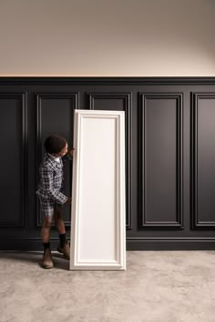 a young man standing in front of an empty white framed canvas on the floor,