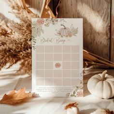 a white pumpkin and some dried leaves on a table with a bridal budget card