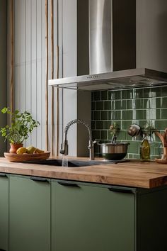 a kitchen with green tiles and wooden counter tops, an oven hood over the sink