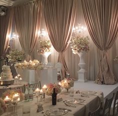 a table set up for a wedding reception with candles and flowers on the tables in front of it