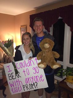 a man and woman standing next to each other holding flowers, teddy bears and a sign that says i couldn't bear to go with anyone else prom?