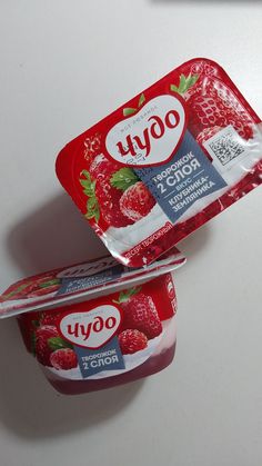 two yogurt containers sitting on top of a white table next to each other