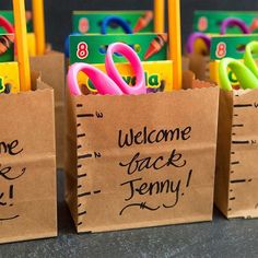 small brown bags with welcome back signs and school supplies in them are lined up on a table