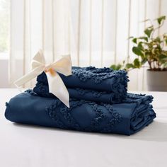 three folded blue towels with a white bow on the top and one folded in dark blue