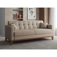 a gray couch sitting on top of a carpeted floor next to a wooden shelf