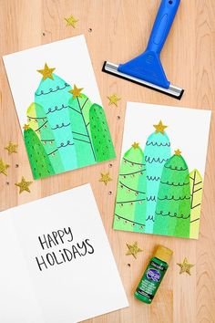 two christmas cards with the words happy holidays on them next to a crafting tool