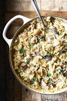 a pan filled with pasta and mushrooms on top of a wooden table