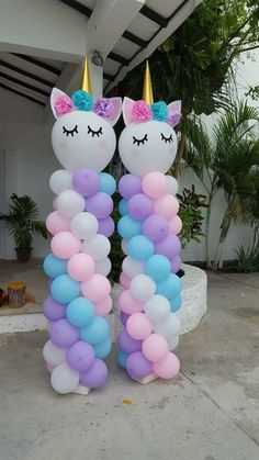 two unicorn balloons are standing next to each other