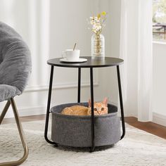 an orange cat laying in a grey basket on top of a table next to a gray chair