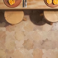 two wooden plates with slices of oranges on them sitting on a counter next to knives and spoons