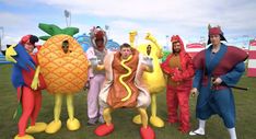 some people are dressed up in costumes for a costume contest on the grass with pineapples and hotdogs