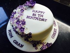 a birthday cake decorated with purple and white flowers