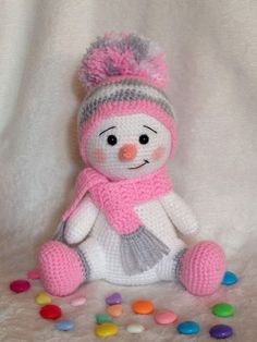 a crocheted snowman with a pink hat and scarf on it's head