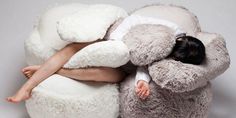 a woman laying on top of a giant stuffed animal chair with her head resting on the pillow