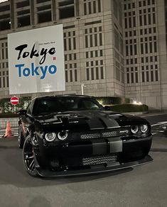 a black and white car is parked in front of a sign that says tokyo tokyo