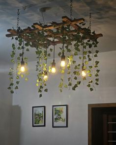 some lights are hanging from a wooden beam in a room with plants growing on the ceiling