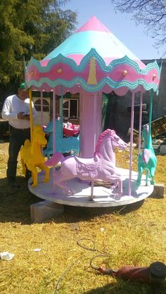 a pink and blue merry go round with horses on the ground next to other toys