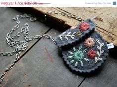 a necklace with flowers on it sitting on top of a piece of wood next to a chain