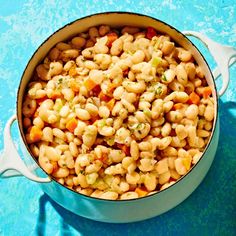 a pot filled with macaroni and cheese sitting on top of a blue surface