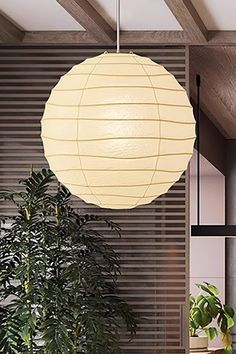 a large white paper lantern hanging from the ceiling over a dining room table and chairs