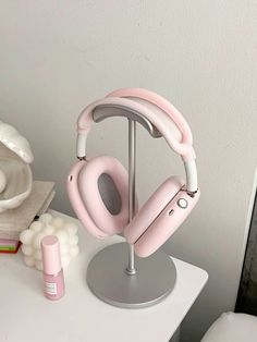 a pair of pink headphones sitting on top of a table next to a white vase