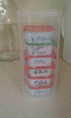 three plastic containers with labels on them sitting on a counter next to a coffee mug