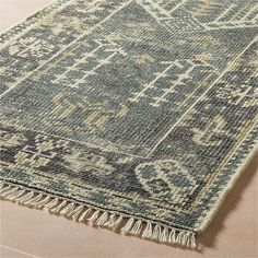 a blue and beige rug with fringes on the bottom, sitting on top of a floor