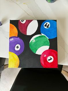 a painting of billiard balls on a black canvas with white letters and numbers painted on it