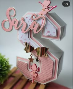 a pink and white card with the word sara hanging from it's center piece