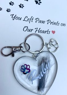 a heart shaped keychain with an animal paw print and the words, you left paw prints on our hearts