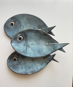 two metal fish sculptures sitting on top of a table