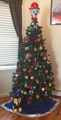 a decorated christmas tree in the corner of a living room with a fireman hat on top