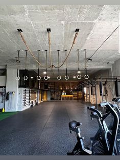 an indoor gym with bikes and exercise equipment on the floor, lights hanging from the ceiling