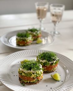 two white plates topped with sandwiches and garnish