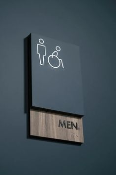 a sign on the wall that says men with a person in a wheelchair behind it