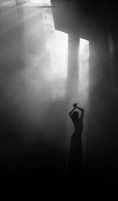 a woman standing in the fog with her arms up