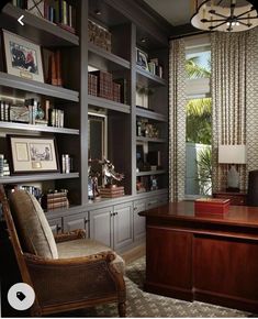 a home office with built - in bookcases, desk and chair next to a large window