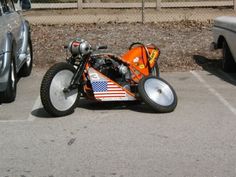 an orange and black motorcycle parked in a parking lot next to a silver pickup truck