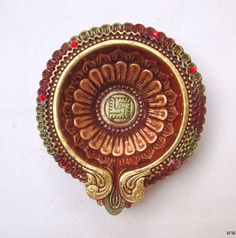 an ornate gold and red brooch with the letter e on it's center