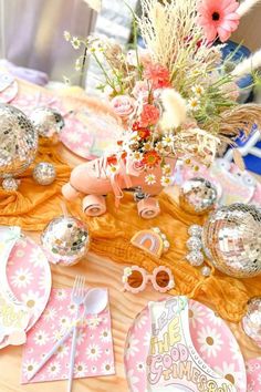 a table topped with lots of pink and gold decorations on top of a wooden table