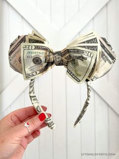 a bow made out of dollar bills is being held by a woman's hand