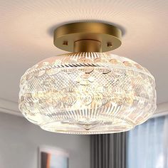 a ceiling light that is hanging from the ceiling in a room with windows and curtains