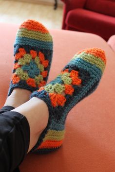 a woman's feet wearing crocheted slippers on top of a couch