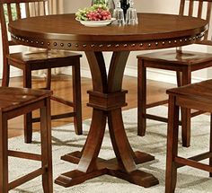 a dining room table with four chairs and a bowl of fruit on top of it