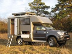 a truck with a camper attached to it parked in a field