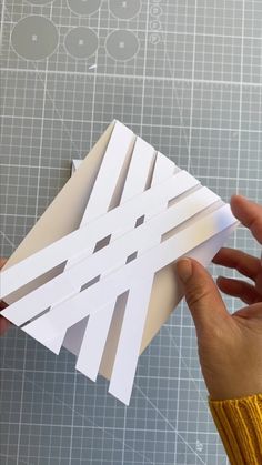 someone is cutting out some white paper on a piece of crafting material with scissors