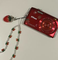 a red camera and some beads on a table