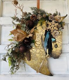 a wreath hanging on the side of a door with pine cones and other things around it