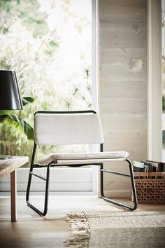 a white chair sitting on top of a hard wood floor next to a table with a lamp