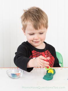 a little boy sitting at a table playing with toys